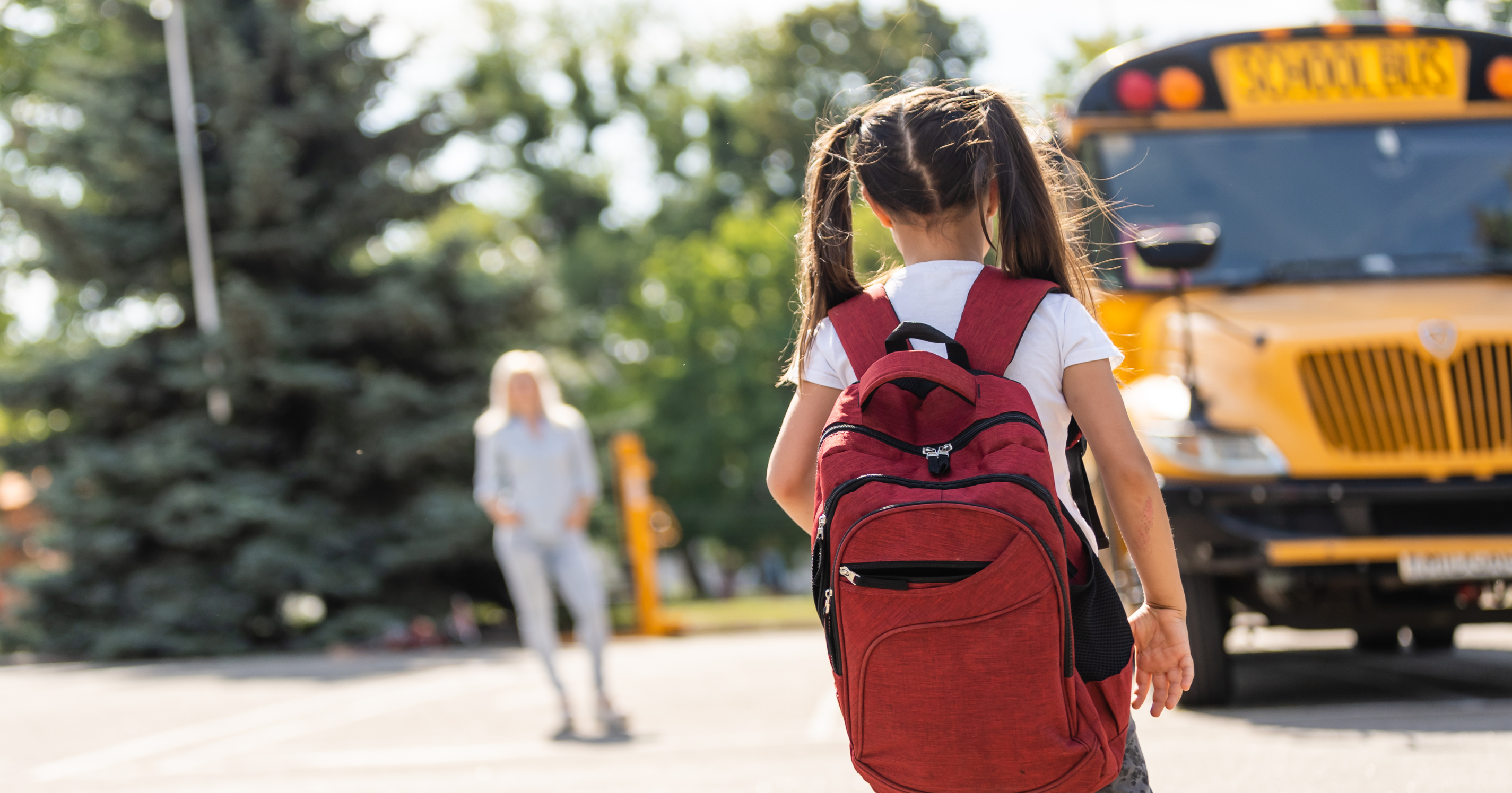girl going to school with bus in the background