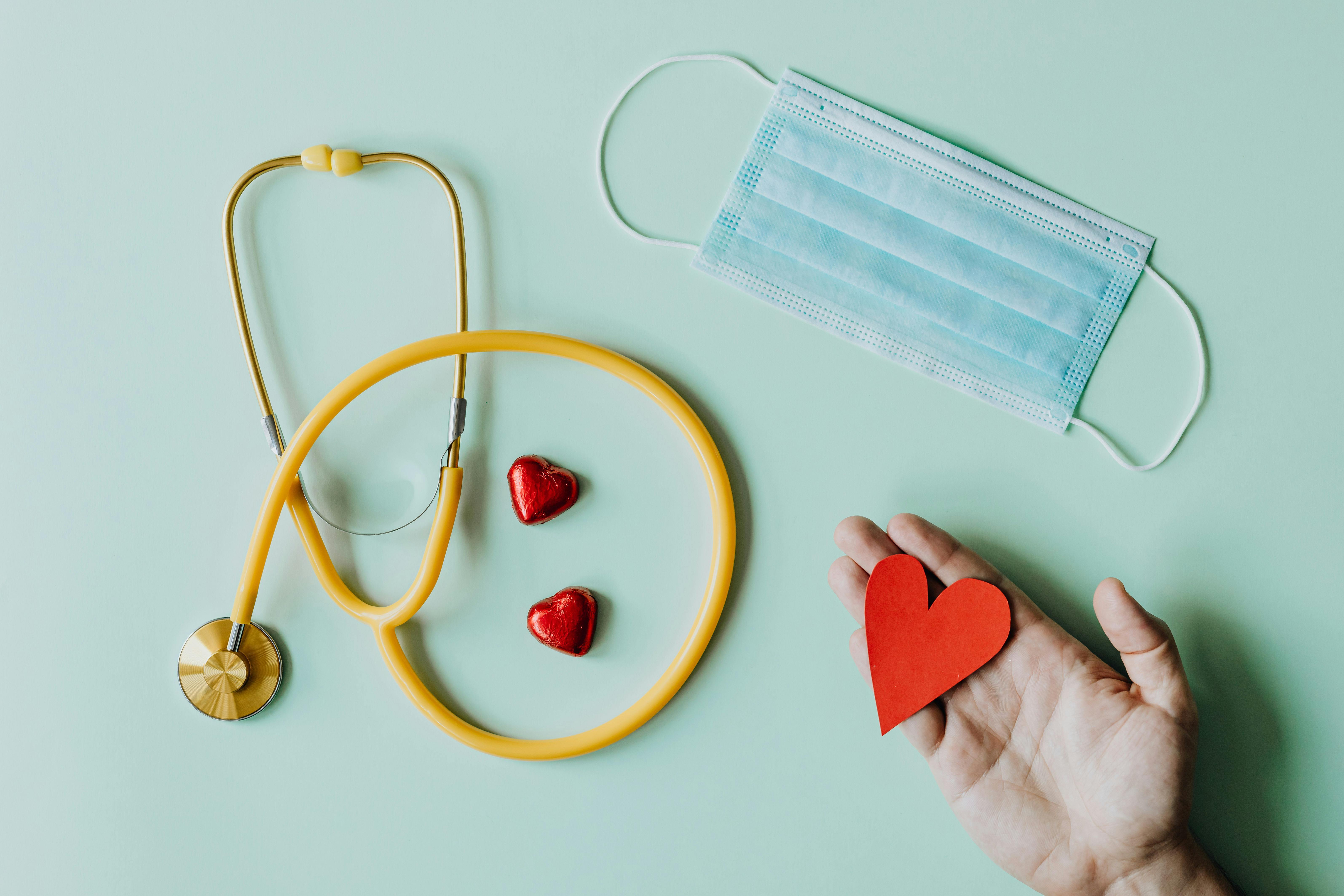 Stethoscope with small red hearts and a hand holding a heart